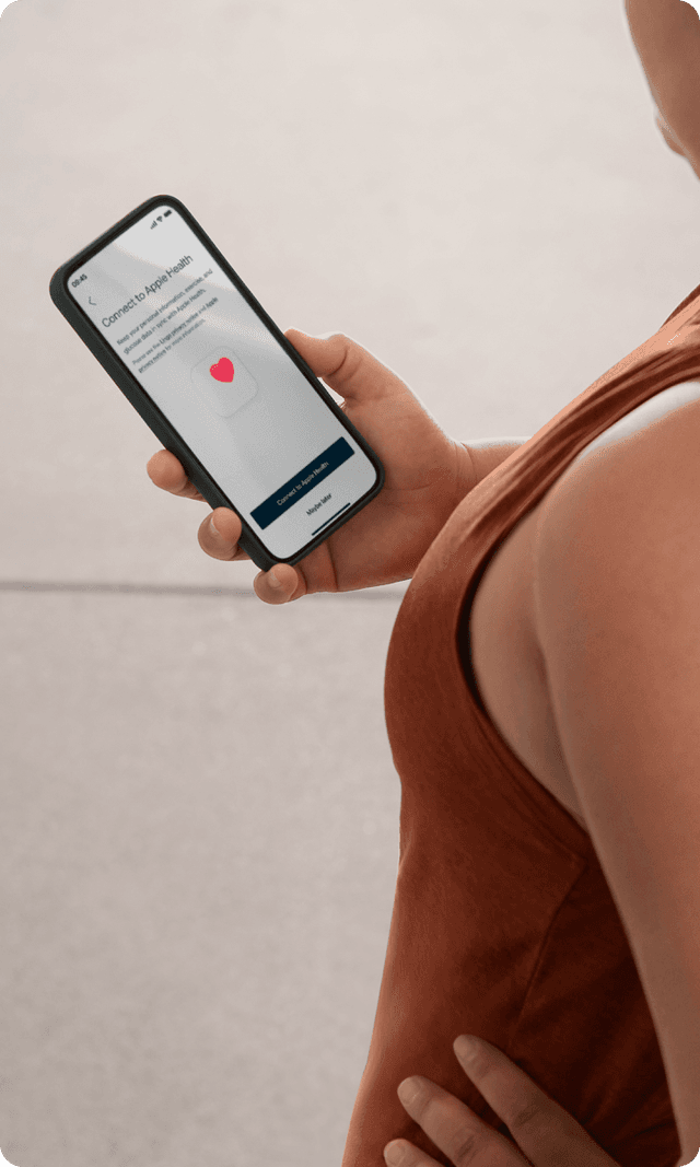 A person in a terracotta colored workout shirt checks her phone 
