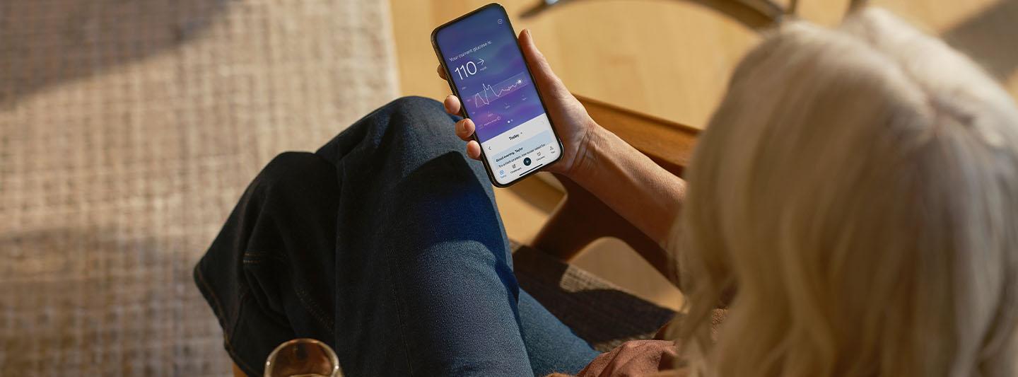  Person looking at glucose data on smartphone
