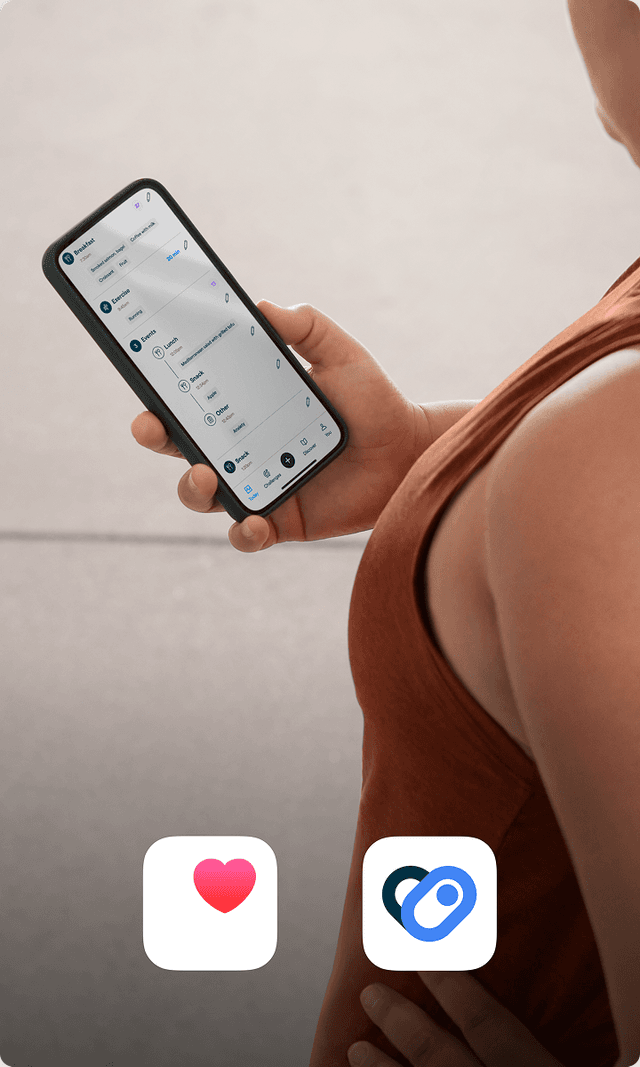 A person in a terracotta colored workout shirt checks her phone 