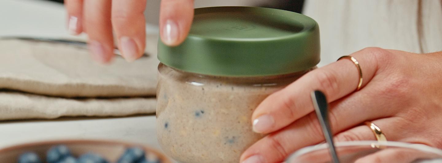 Person opening a jar of blueberry overnight oats