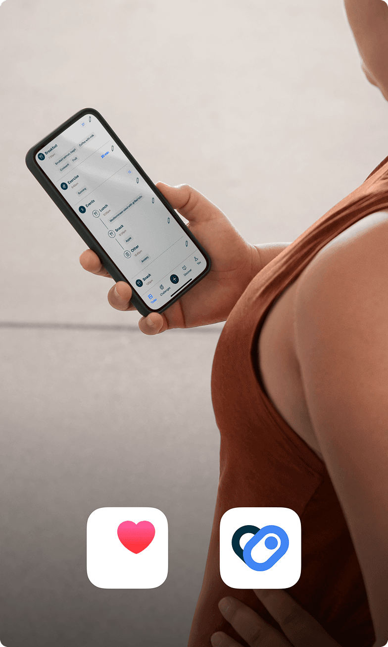 A person in a terracotta colored workout shirt checks her phone 