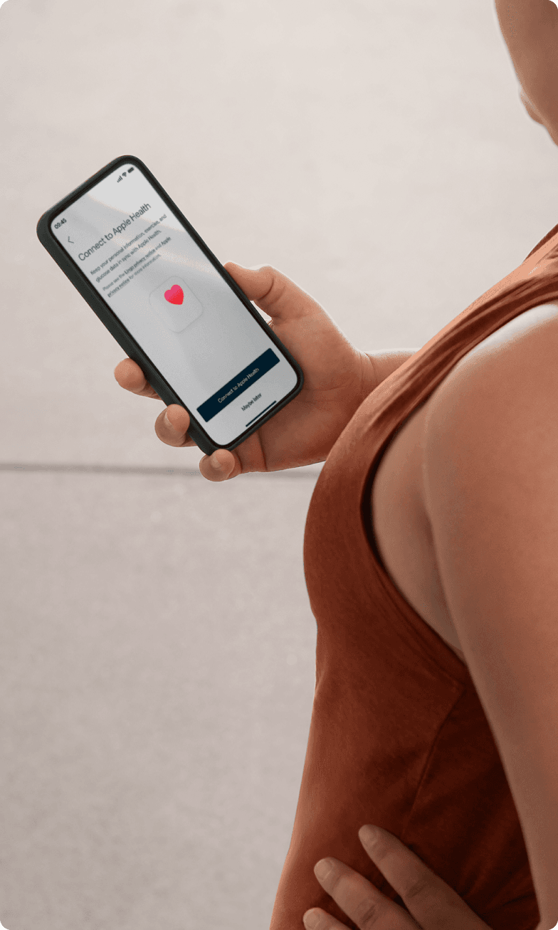 A person in a terracotta colored workout shirt checks her phone 