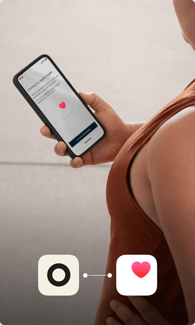 A person in a terracotta colored workout shirt checks her phone 