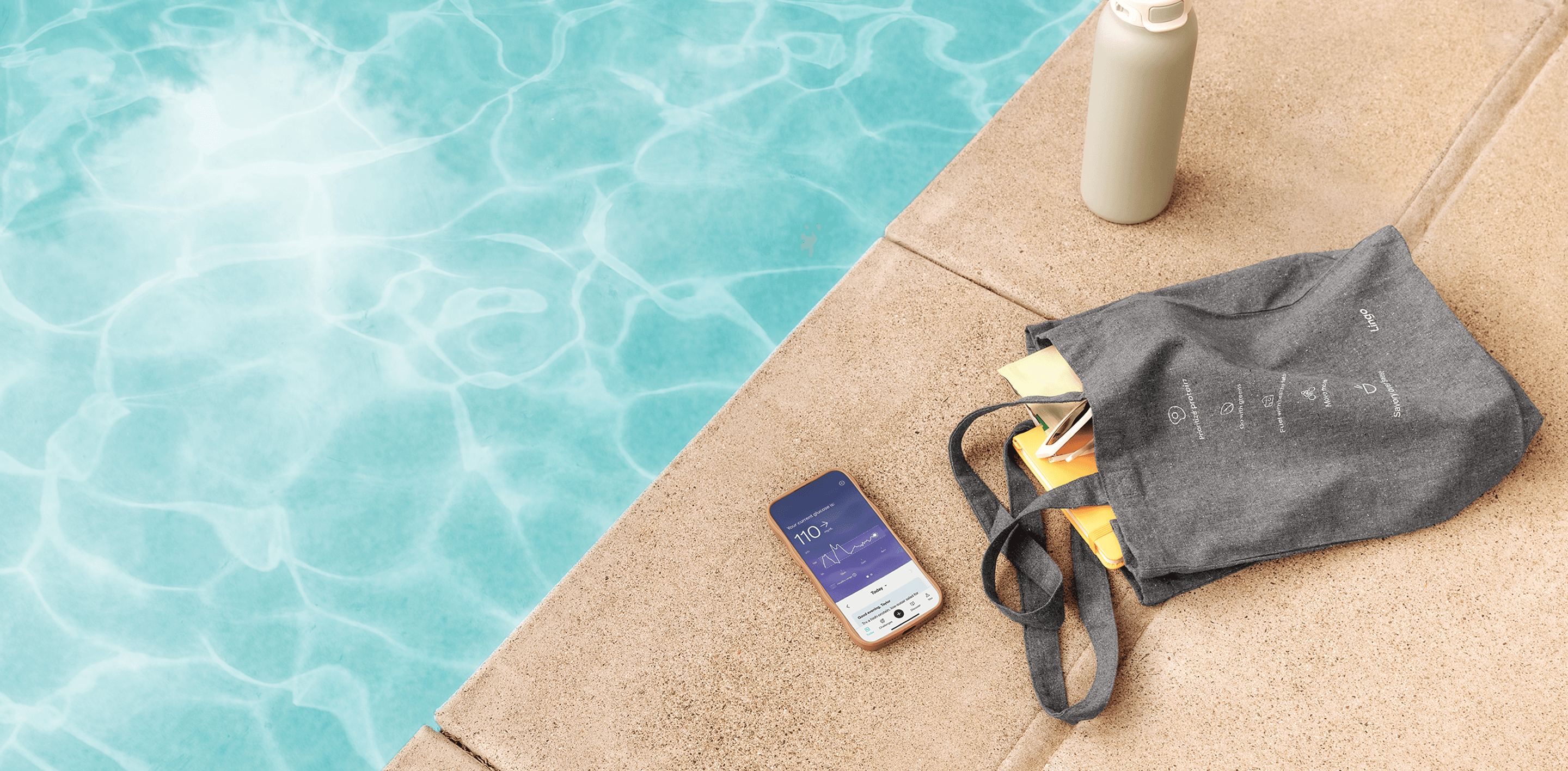 A recycled tote bag, and a phone showing the Lingo application on a pool deck next to sparkling blue water. 