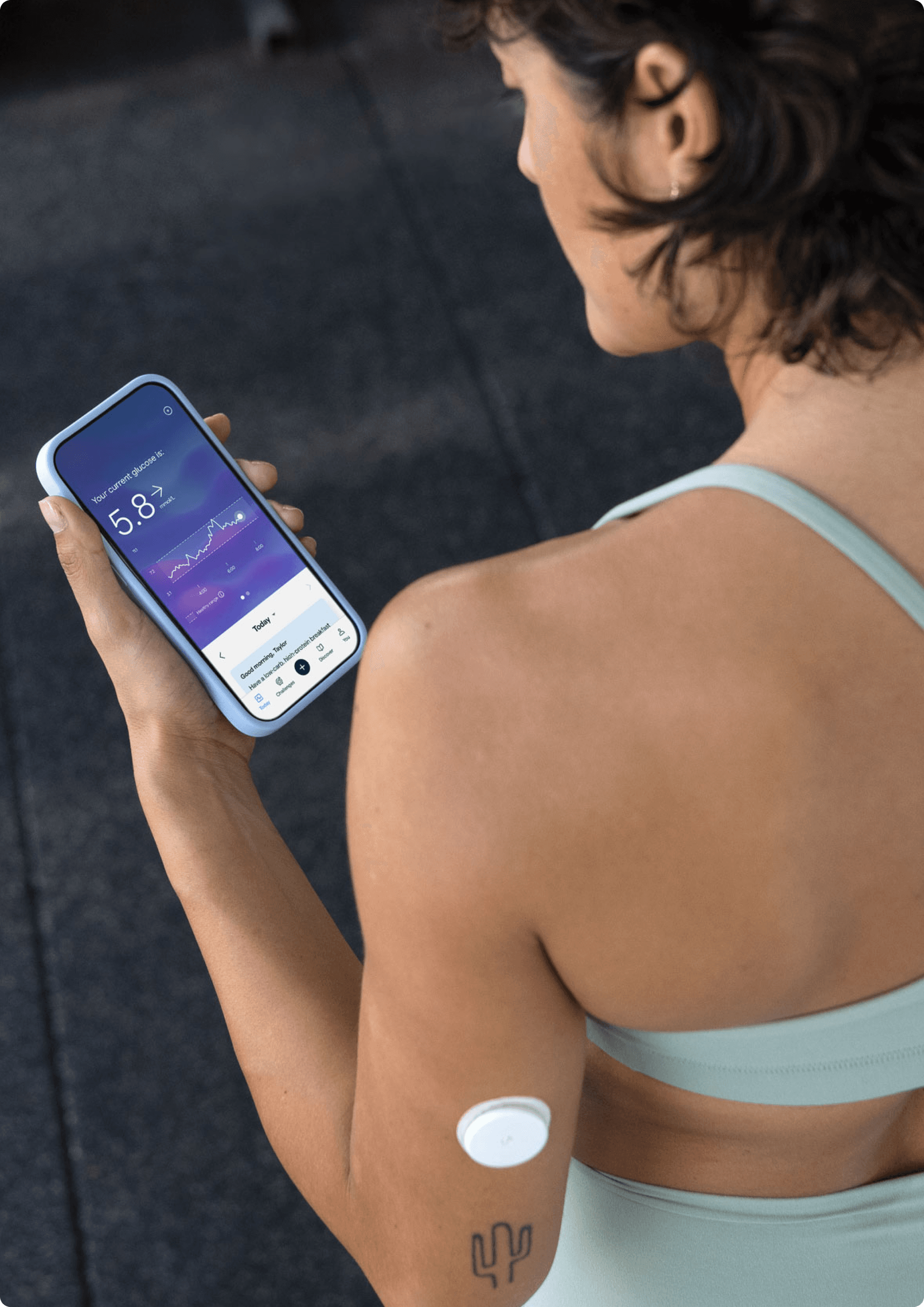 A woman in workout clothing looking at the Lingo app on her phone
