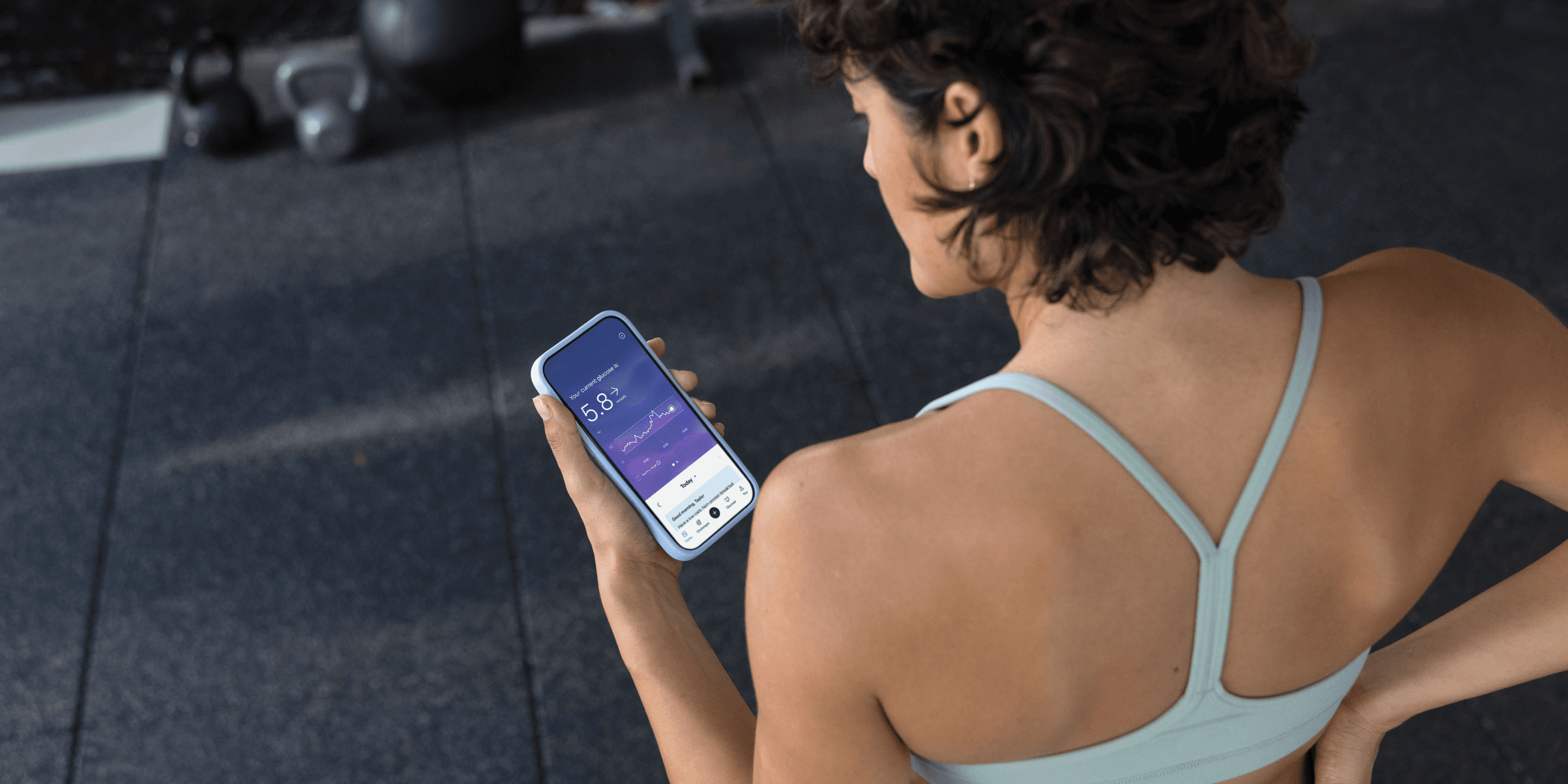 Woman in sportswear wearing a CGM and looking at the Lingo app