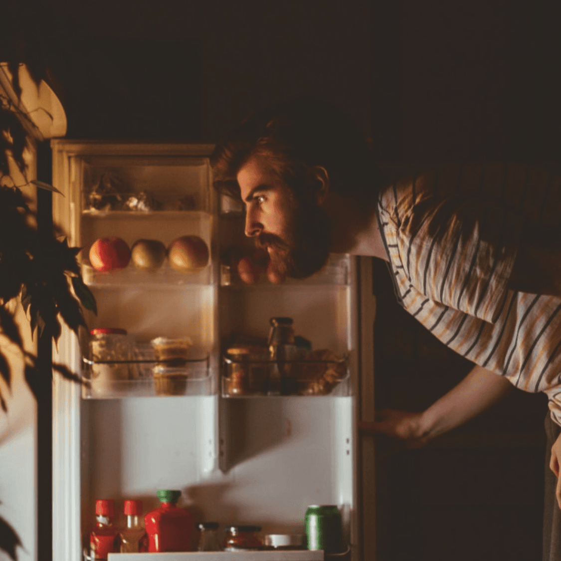 Man looking into fridge at night.
