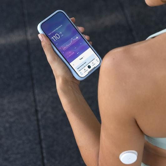 Woman in sportswear wearing a CGM and looking at the Lingo app