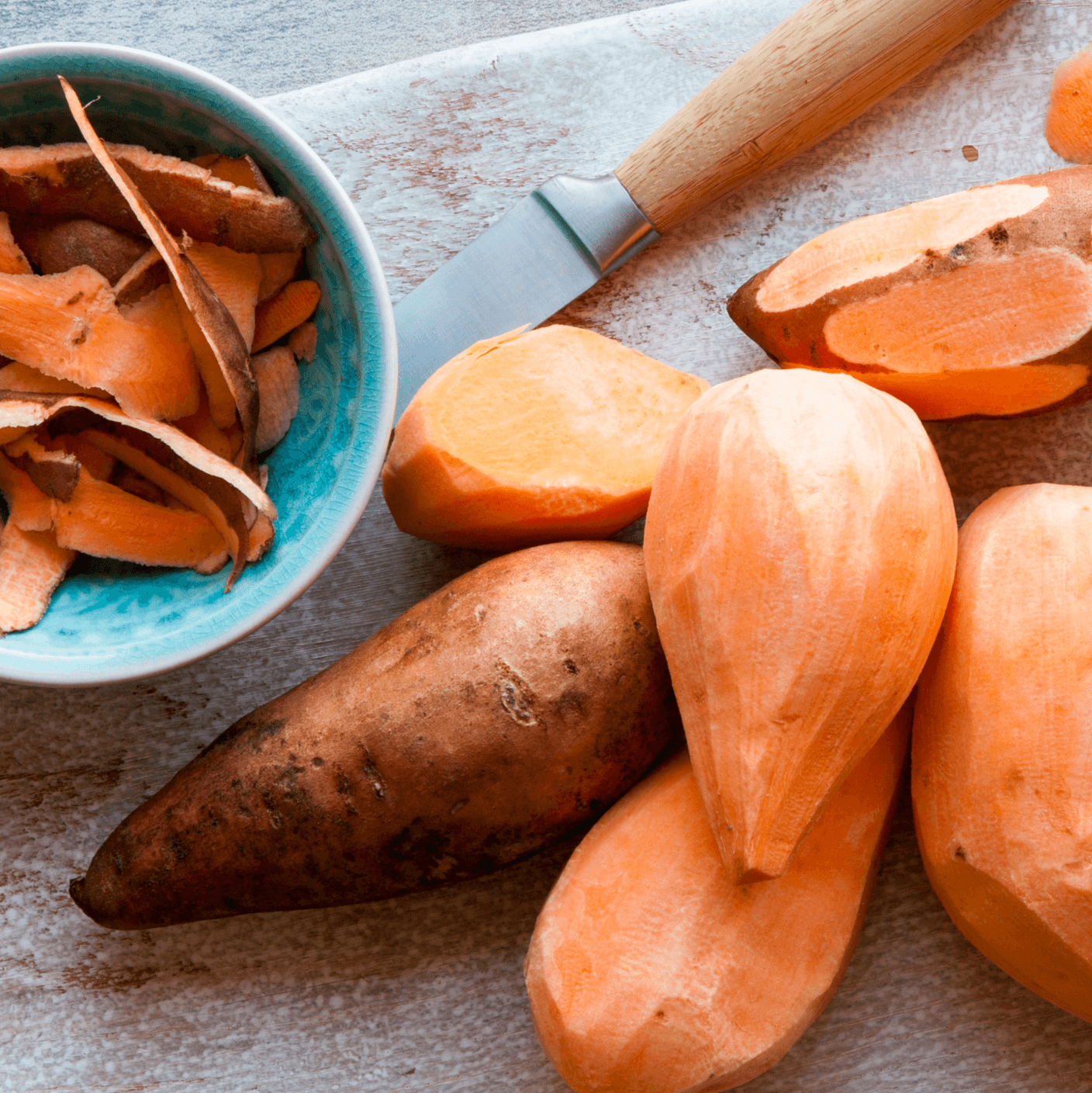 Sweet potatoes on board for peeling.