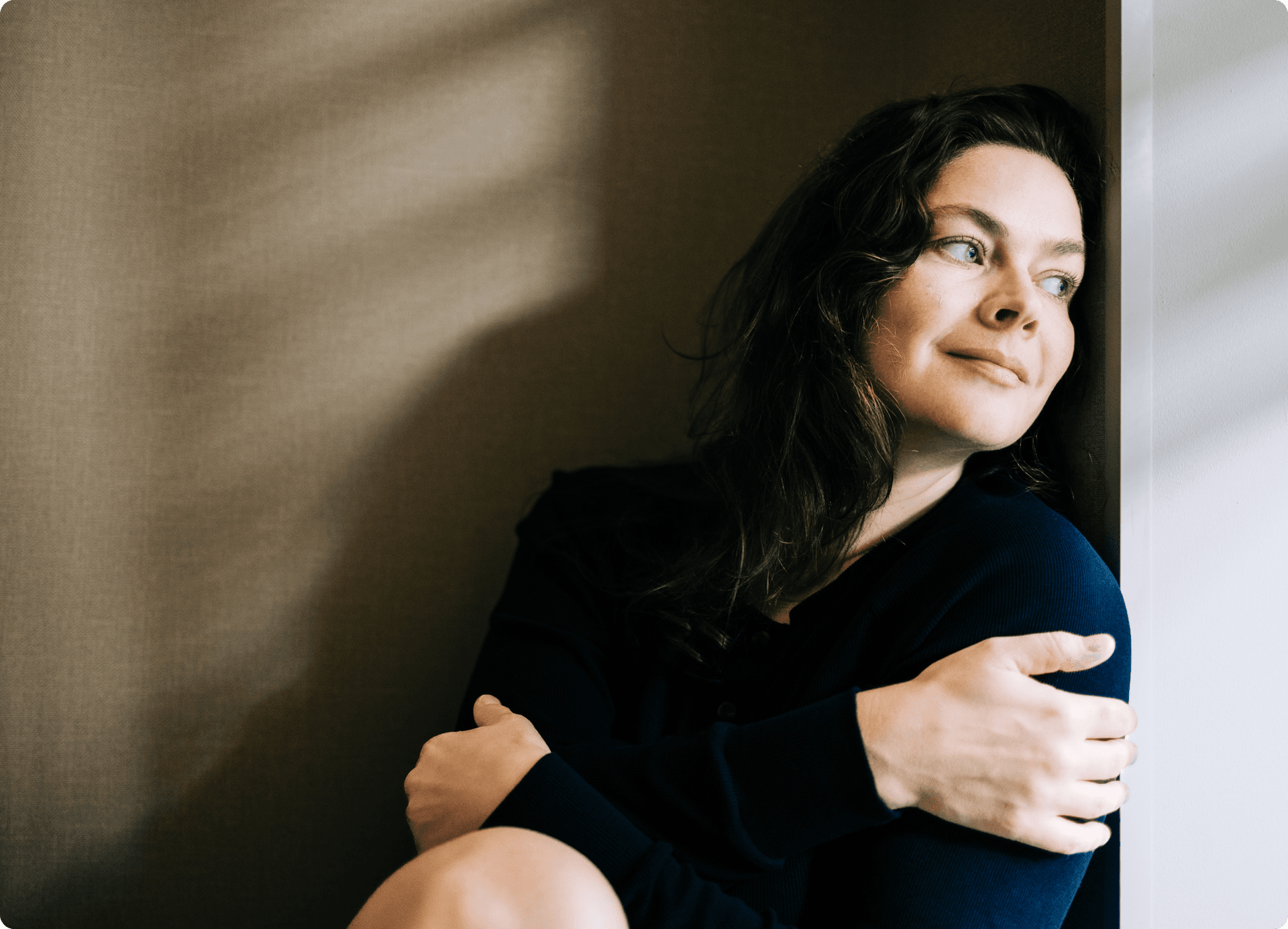 A woman smiling and leaning against a wall
