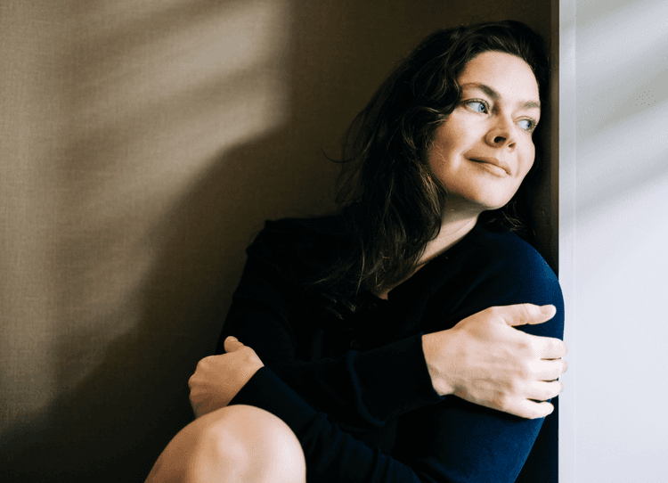 A woman smiling and leaning against a wall