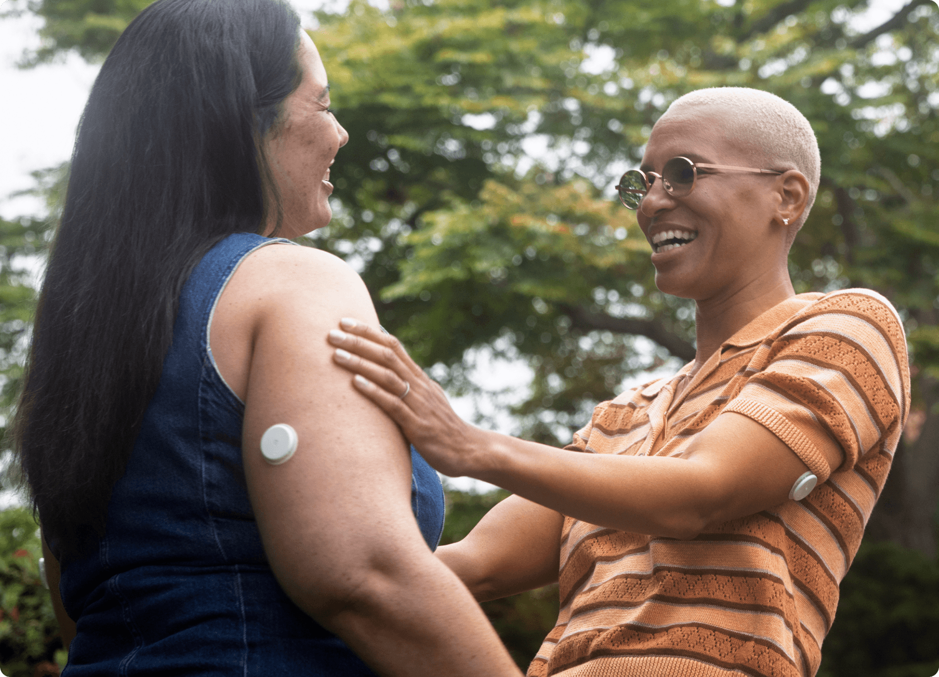 Two women wearing the Lingo sensor in an embrance