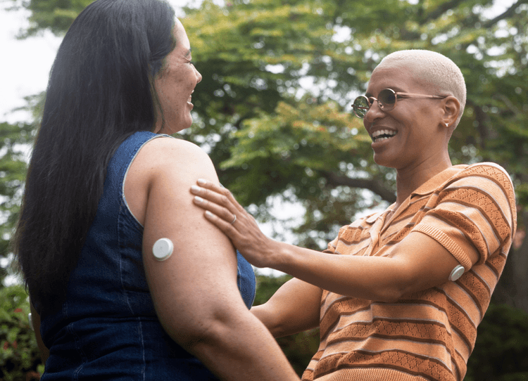 Two women wearing the Lingo sensor in an embrance