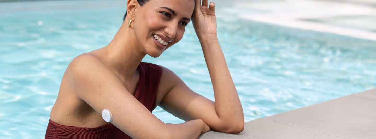 Person in swimming pool with CGM on arm