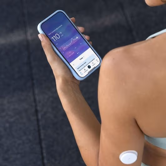 Woman in sportswear wearing a CGM and looking at the Lingo app