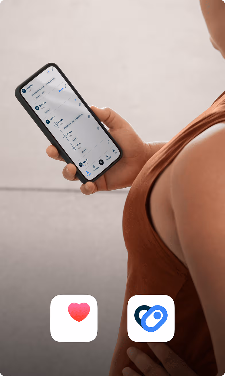 A person in a terracotta colored workout shirt checks her phone