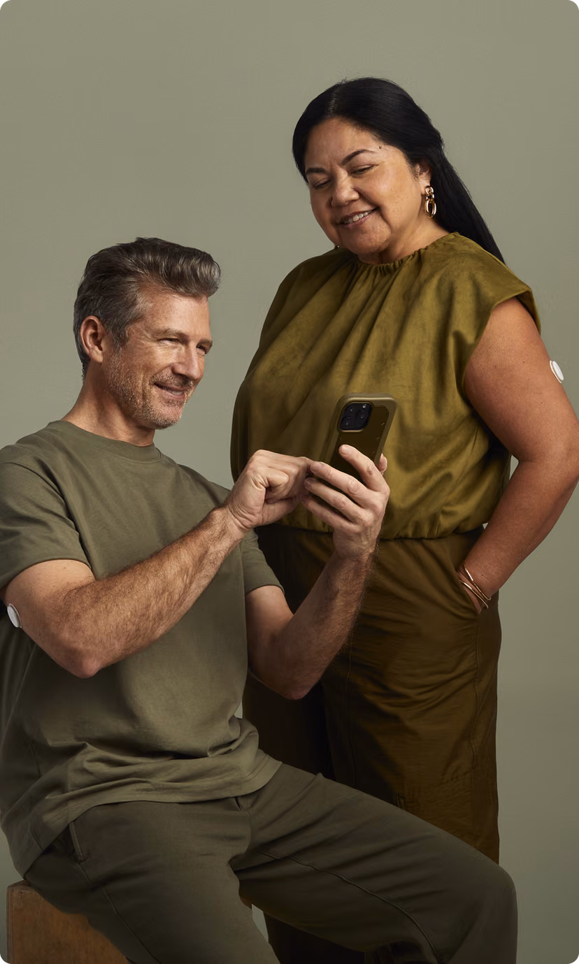 A man sitting looking at his phone and a woman looking over his shoulder