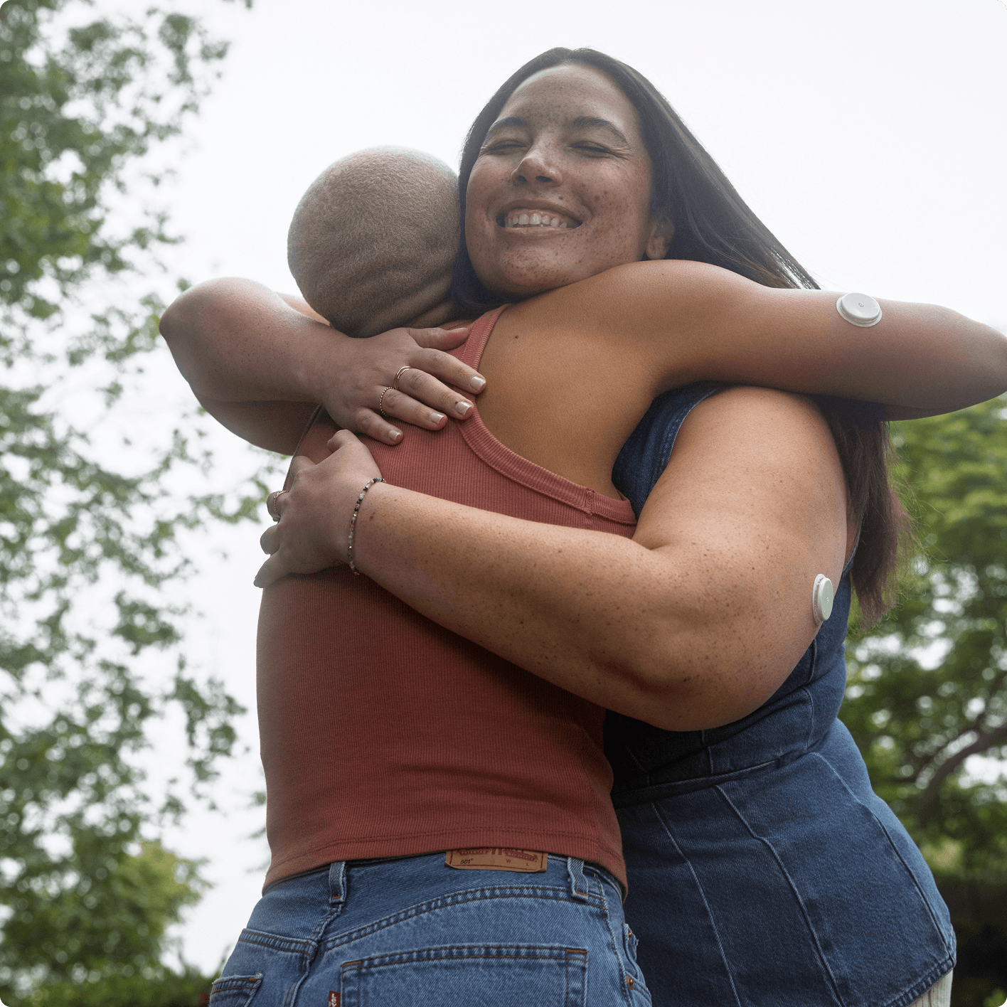 Two women wearing the Lingo sensor while hugging each other.