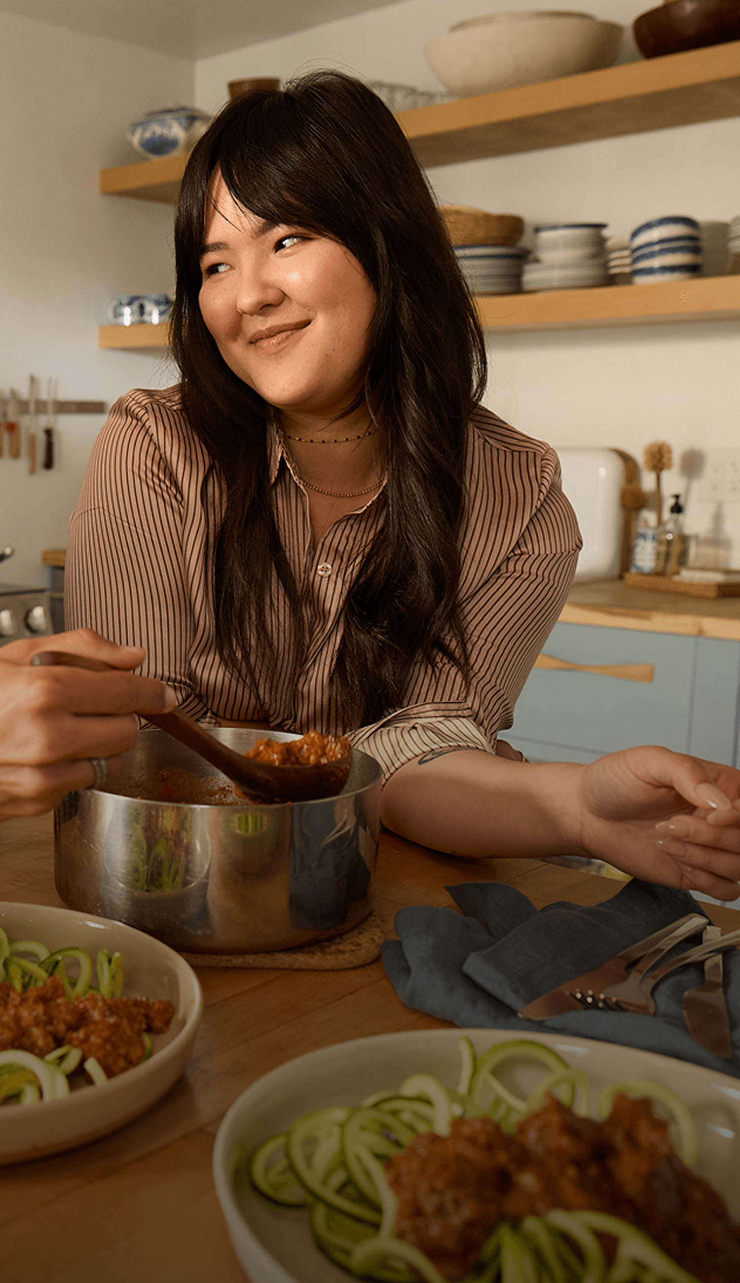 A man wearing a Lingo sensor serving zoodles to a woman in a kitchen