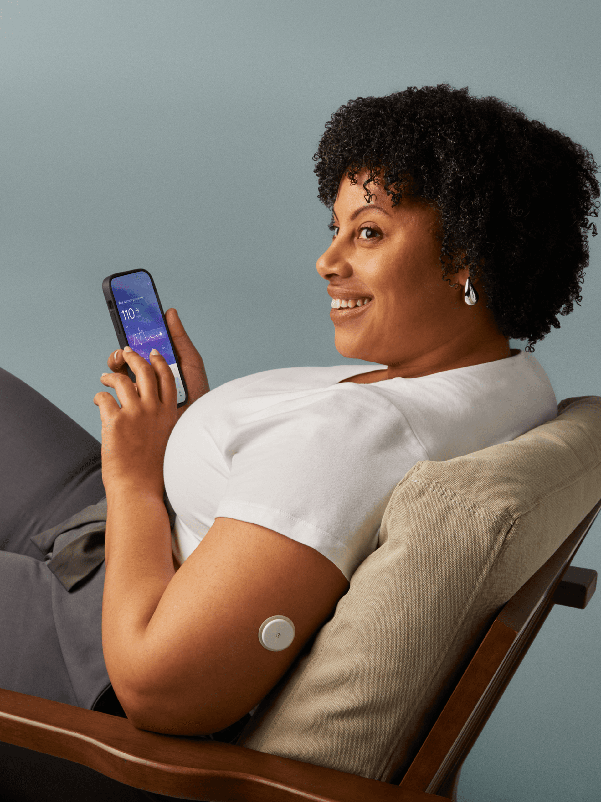Woman sitting looking at the Lingo app on her phone.
