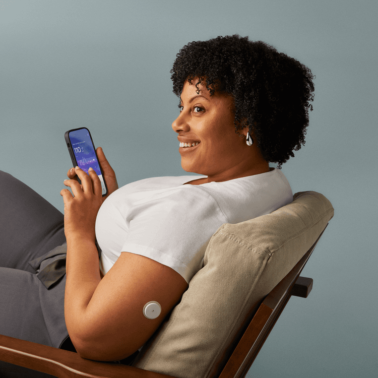 Woman sitting looking at the Lingo app on her phone.