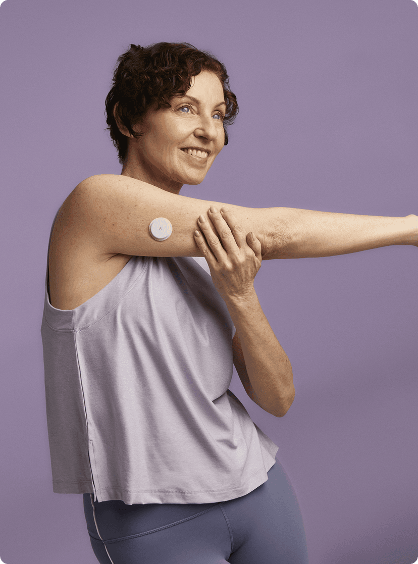 A woman stretching wearing a Lingo Continuous Glucose Monitor