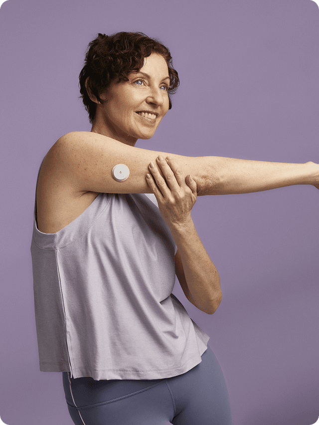 A woman stretching wearing a Lingo Continuous Glucose Monitor