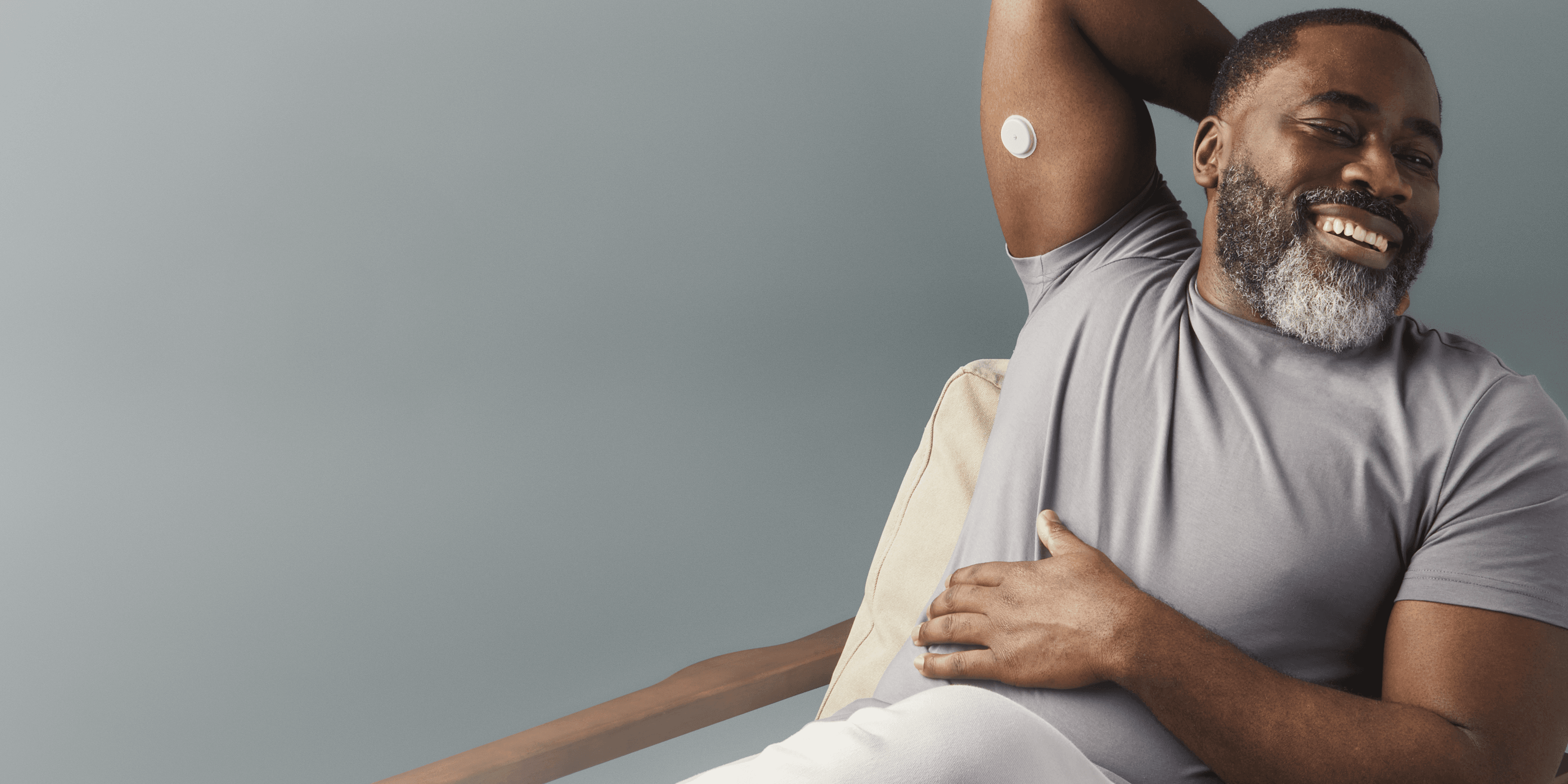 A smiling man wearing a biosensor