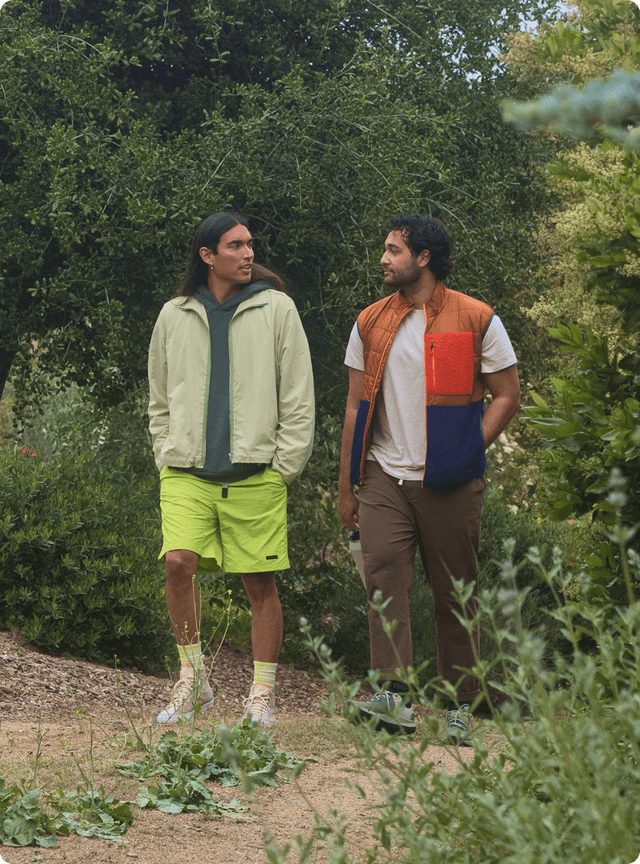 Two male friends going on a walk in a park.
