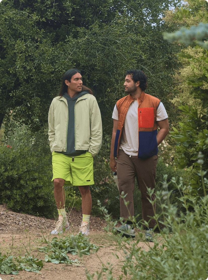 Two male friends going on a walk in a park.