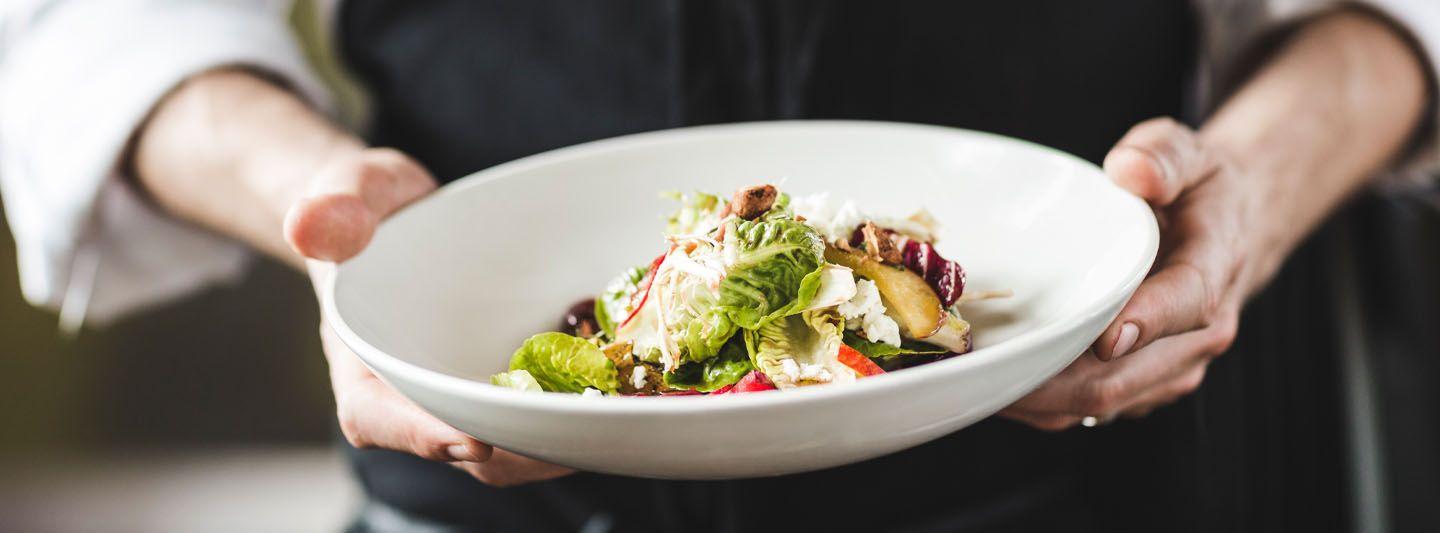Person holding bowl of healthy restaurant food