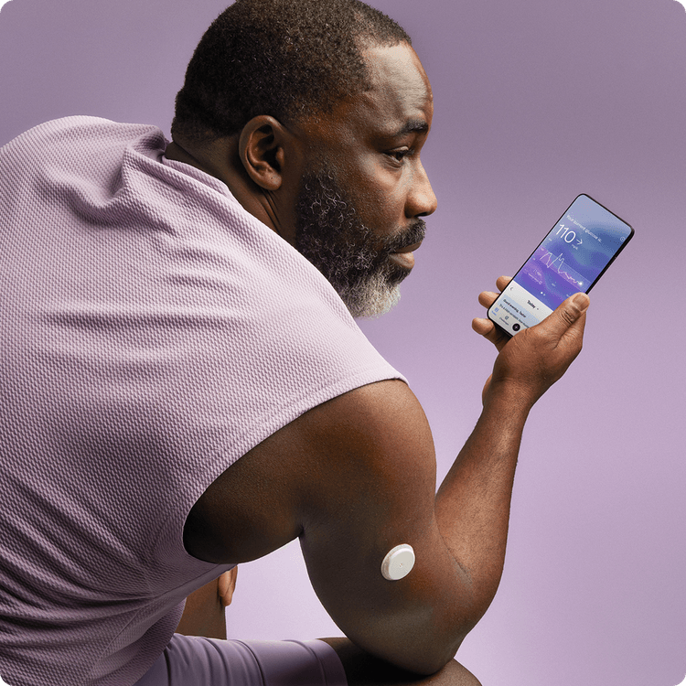 A man in a sleeveless shirt wearing a Lingo biosensor while looking at the Lingo app.