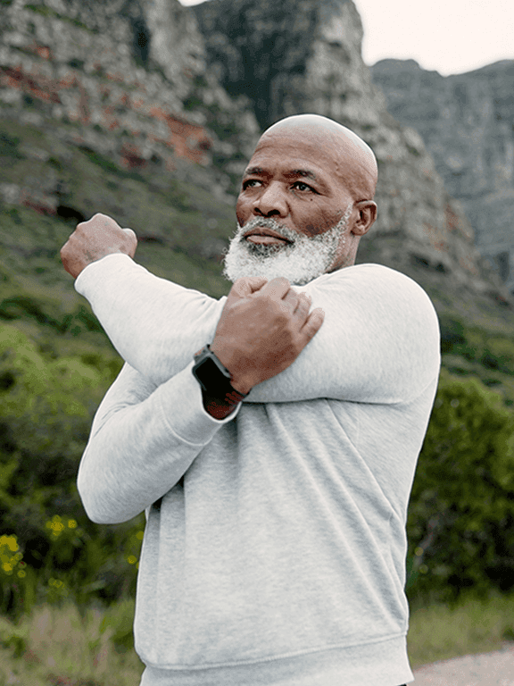 A man stretching his shoulder in nature