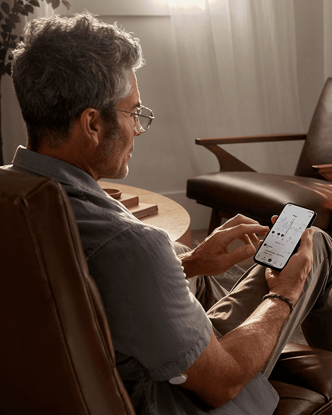 A picture of a man seated and looking at the Lingo app on his phone