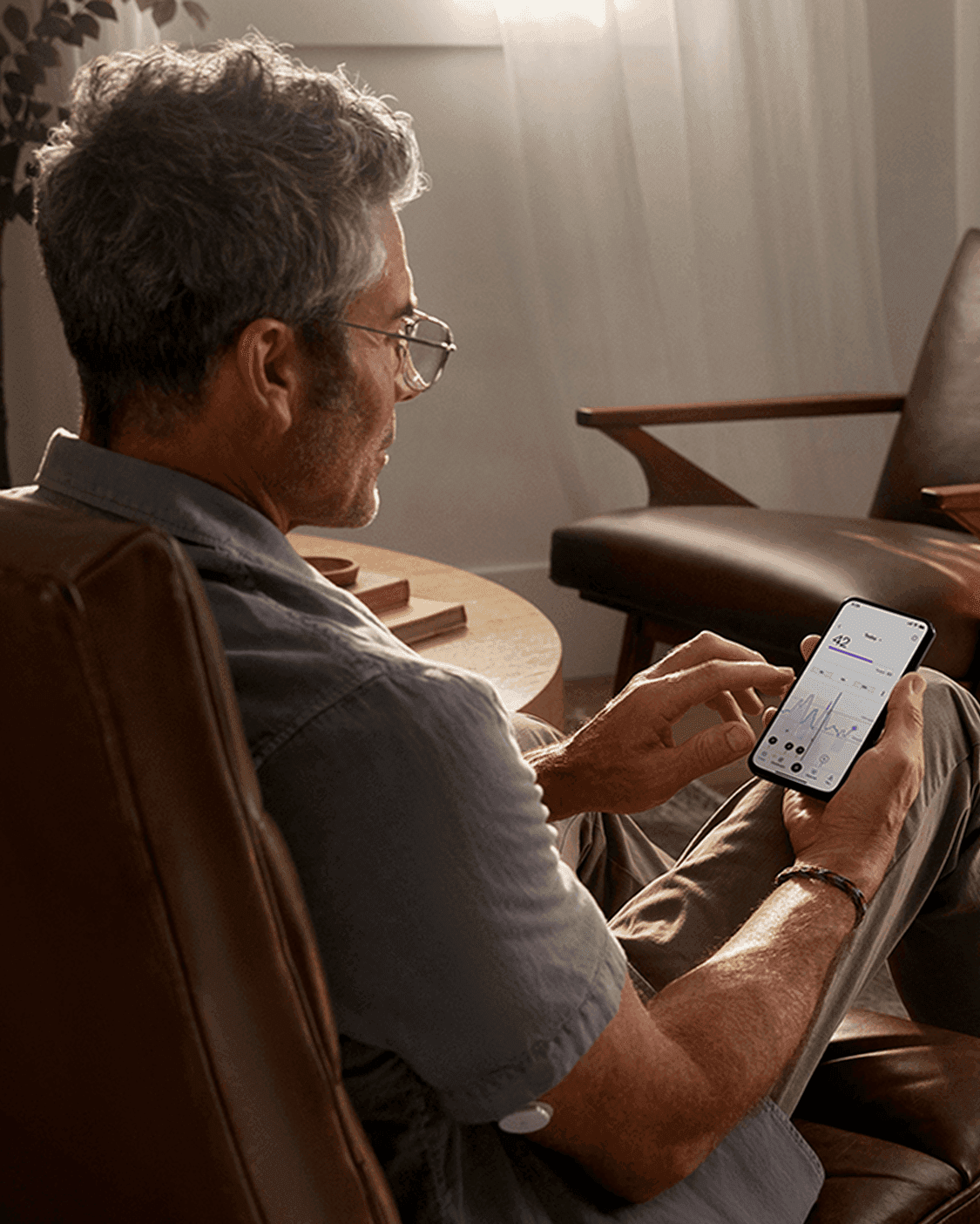 A picture of a man seated and looking at the Lingo app on his phone