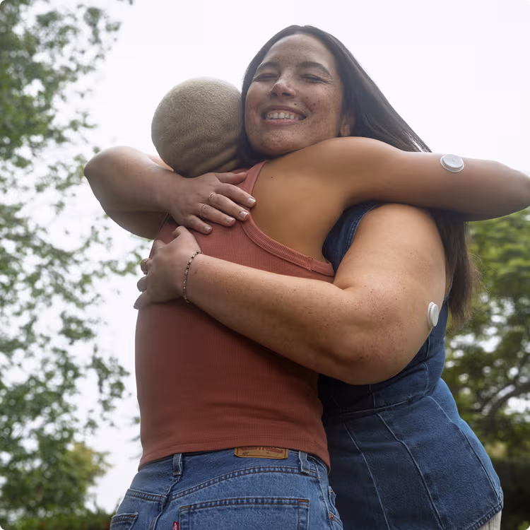 Two women wearing the Lingo sensor while hugging each other.