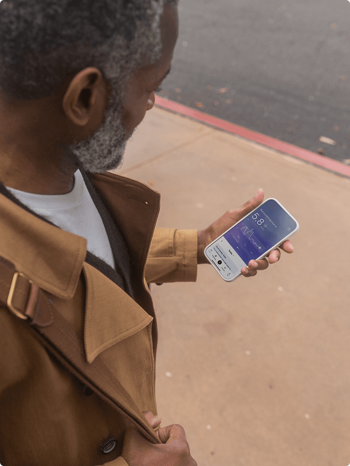 A person holding a smartphone displaying the Lingo app with a glucose reading.