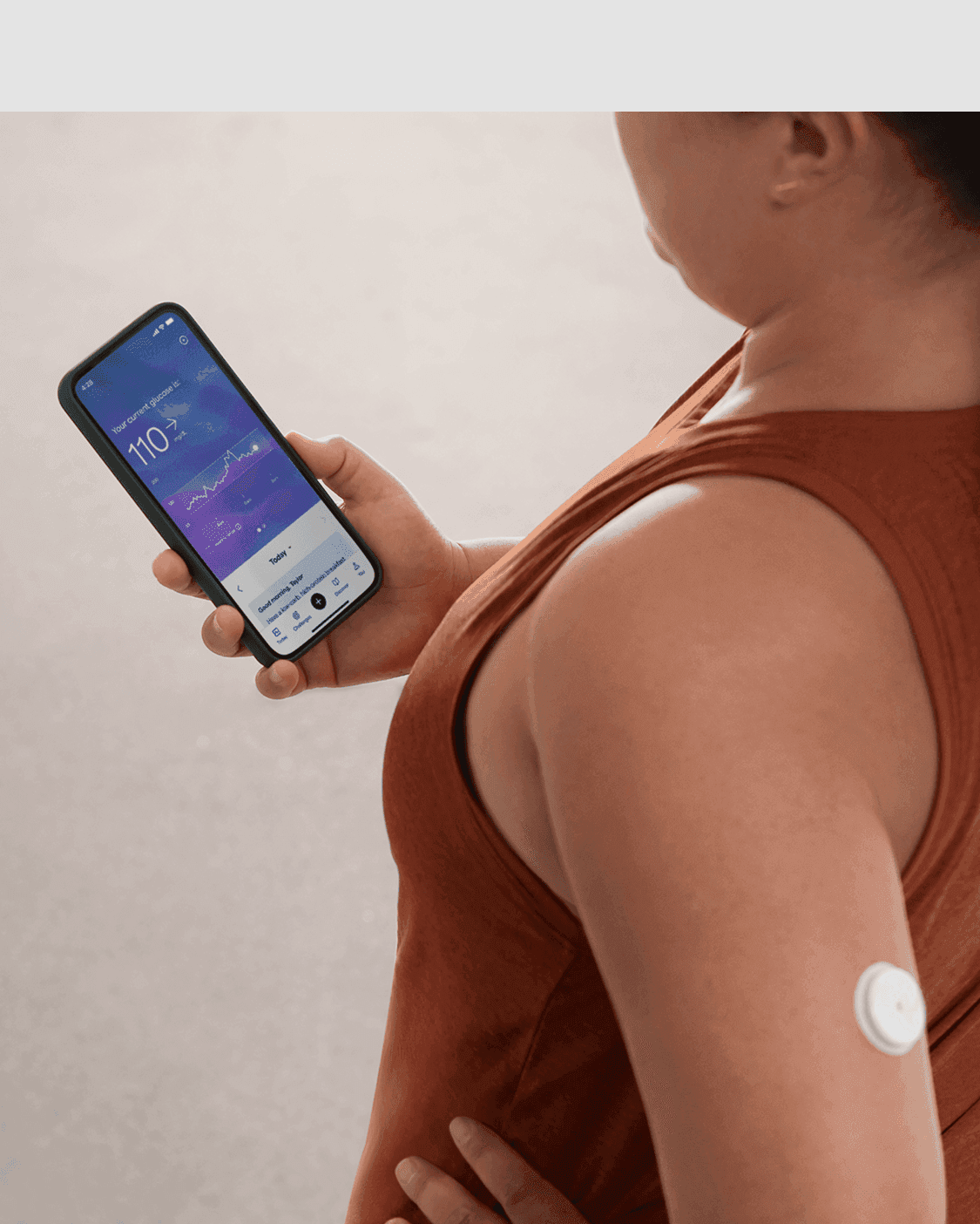 Woman wearing a Lingo cgm and checking the Lingo app on her phone