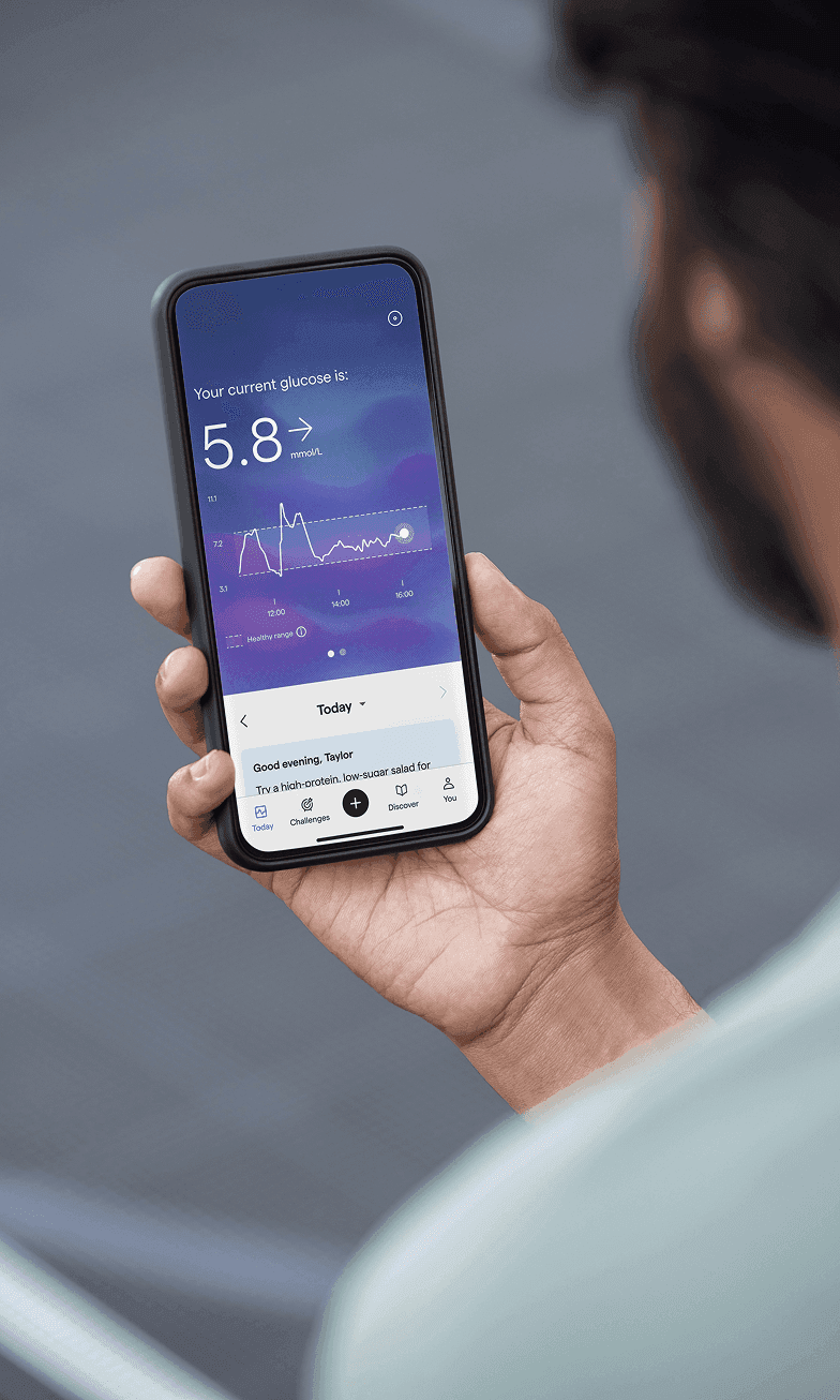 A person holding a smartphone and looking at their Lingo glucose graph.