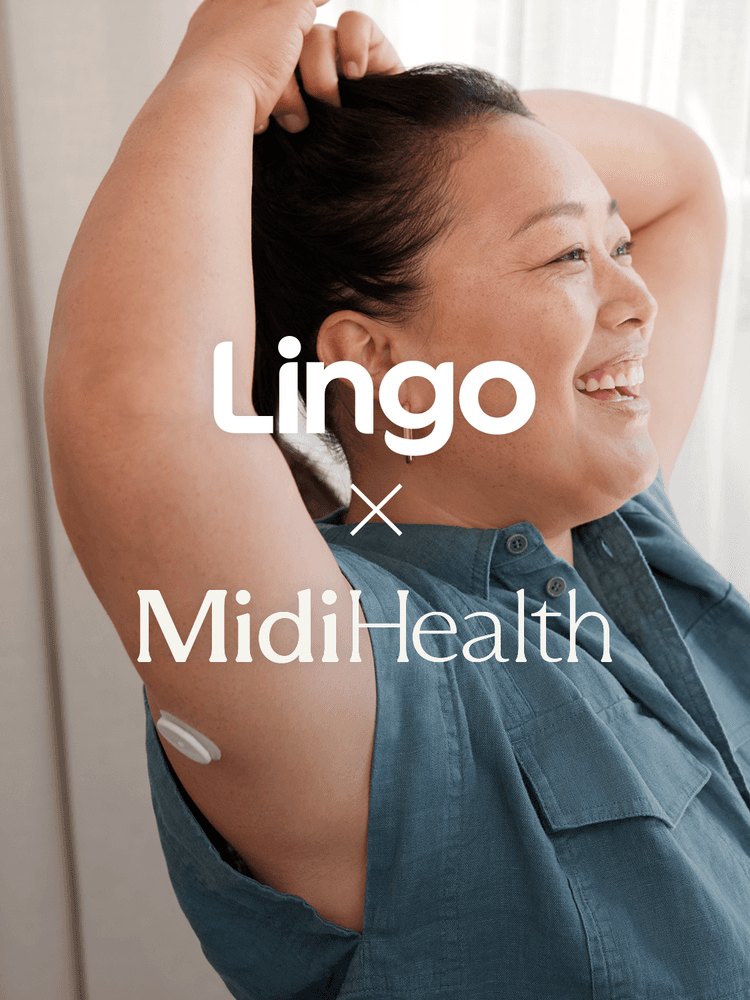 A smiling woman in a blue shirt with her arms over her head.